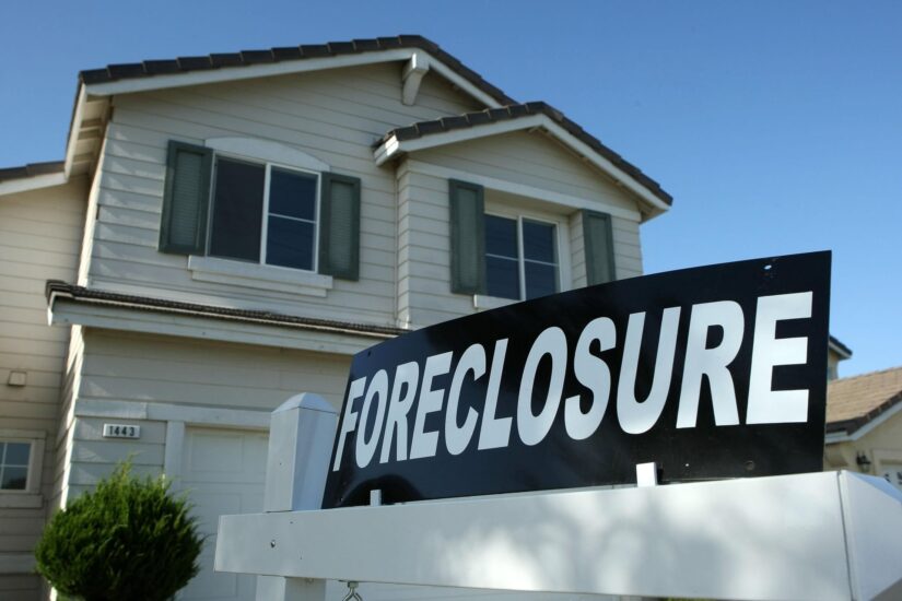 Foreclosure sign in front of a two story house